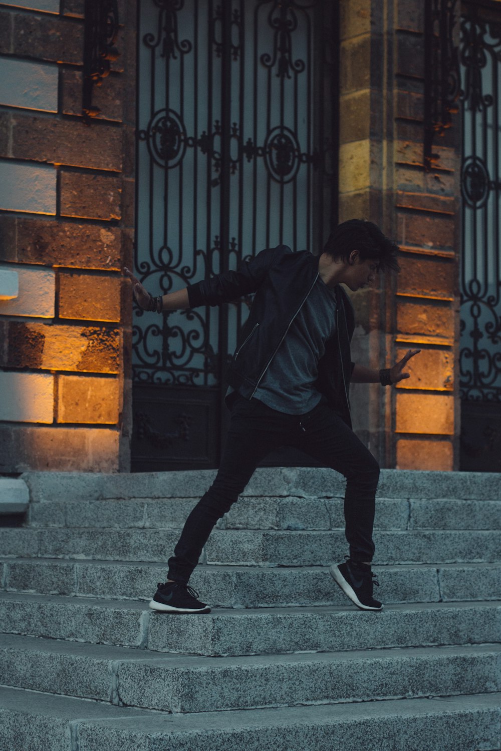 man in black jacket and black pants walking on gray concrete stairs