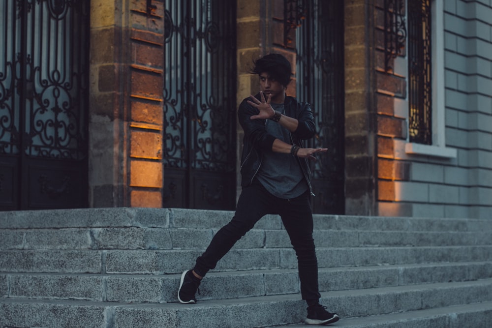 man in black t-shirt and black pants sitting on concrete stairs