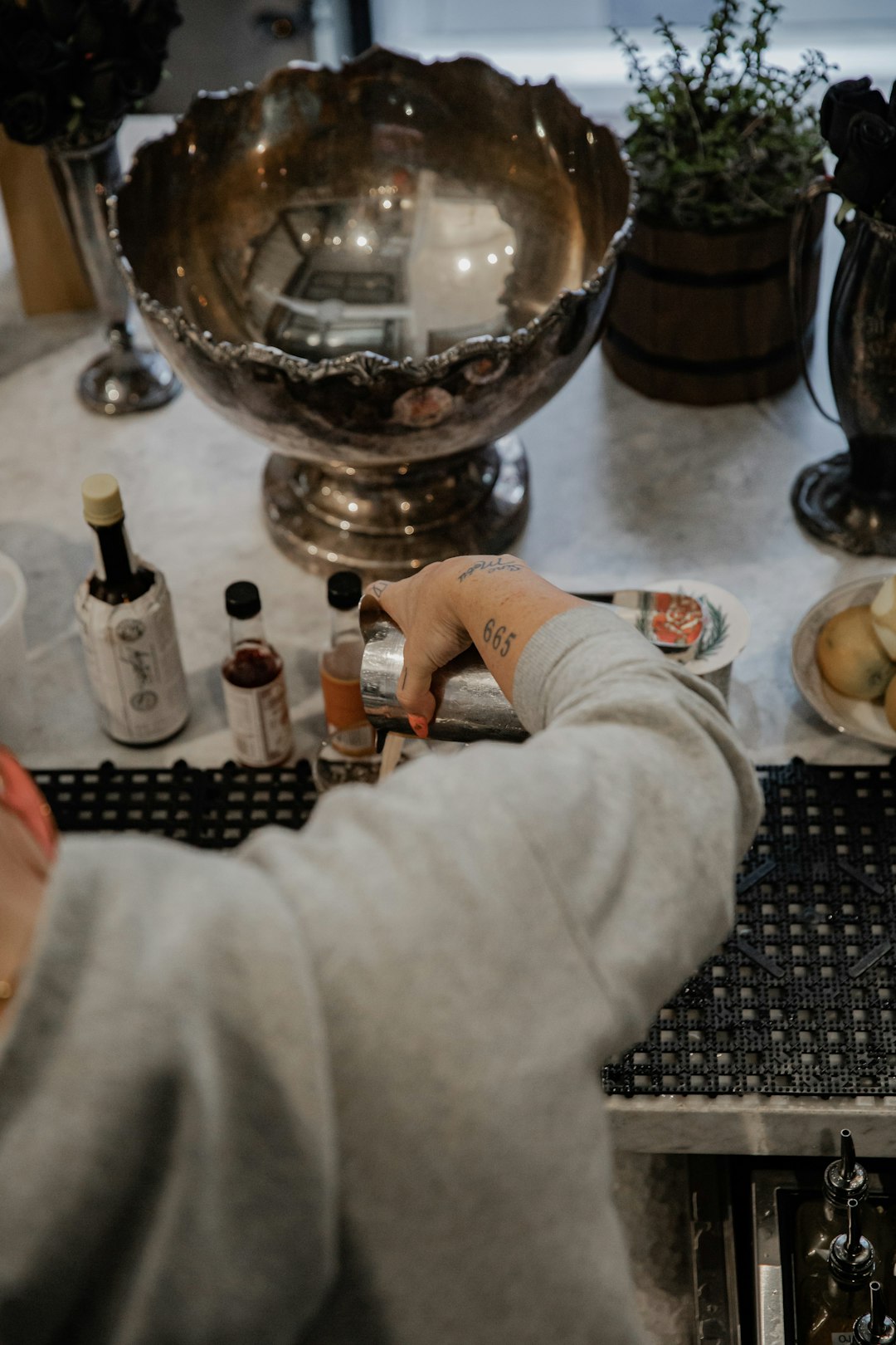 person in white long sleeve shirt holding clear glass bottle