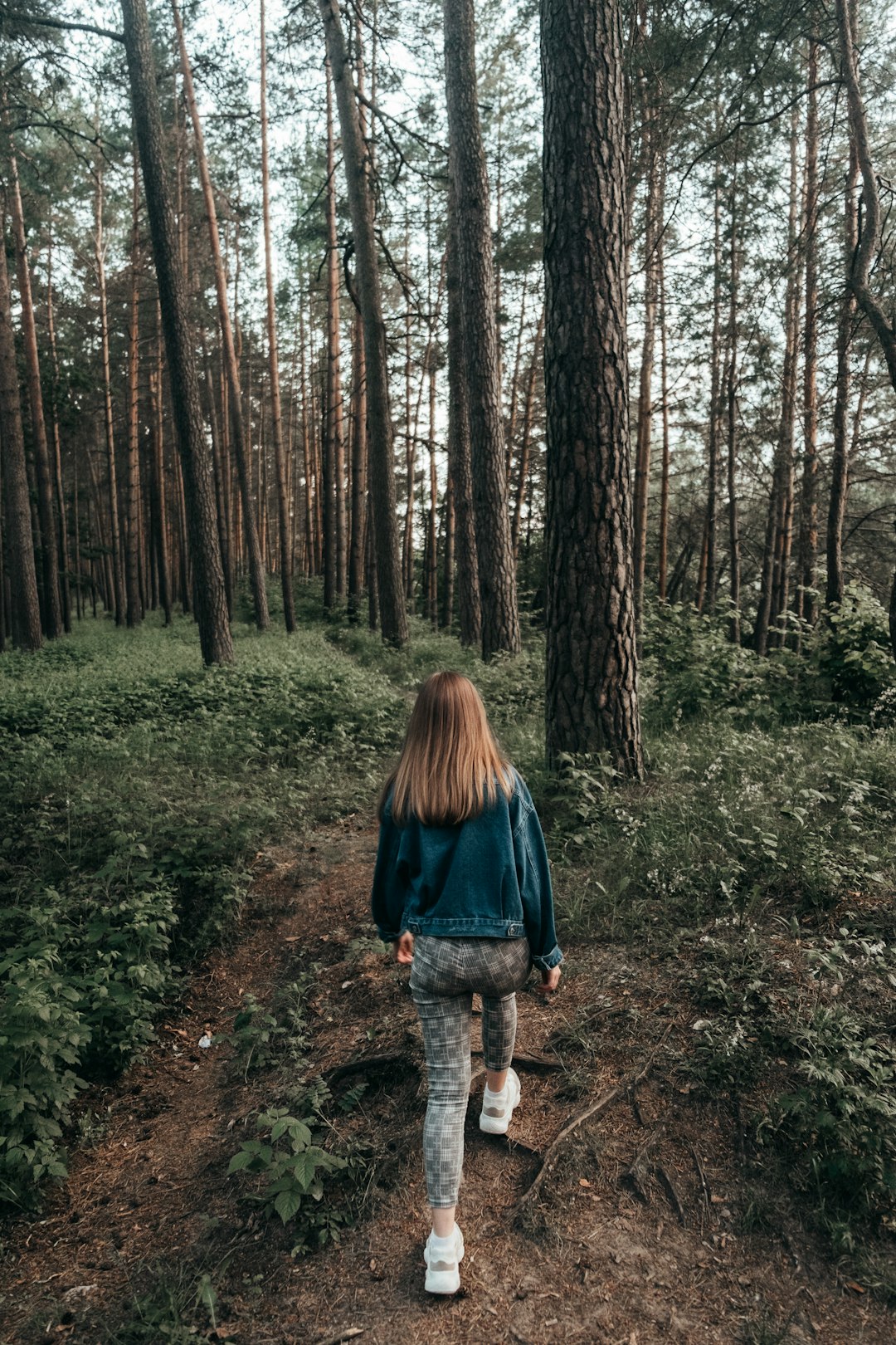 woman in black jacket walking on forest during daytime