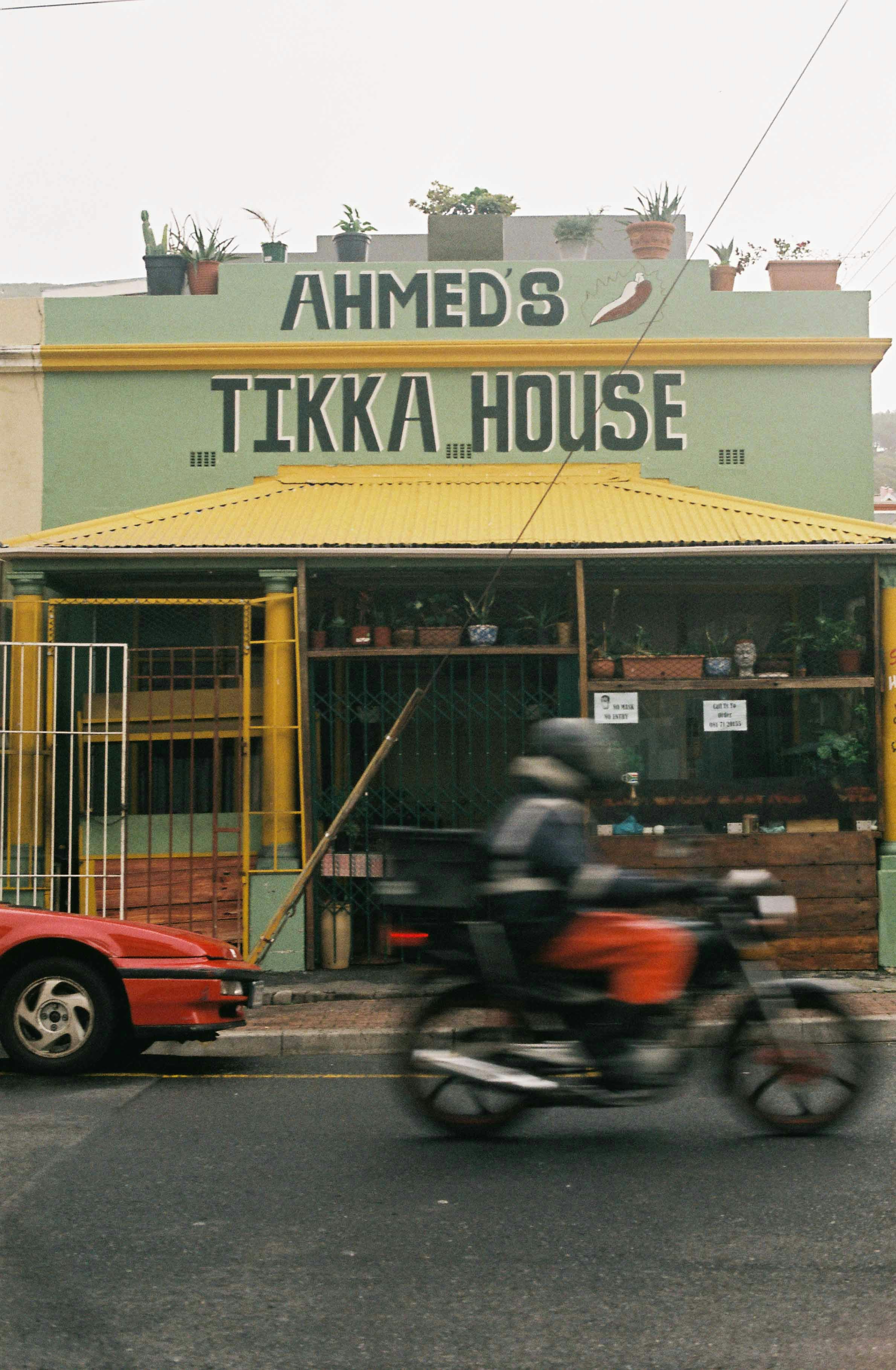 man in black jacket riding motorcycle in front of red car during daytime