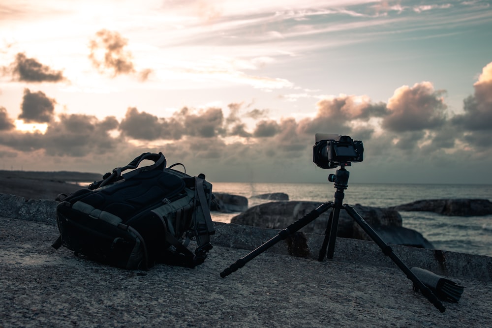 black dslr camera on tripod on gray sand during sunset