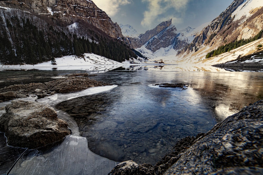 body of water near mountain during daytime