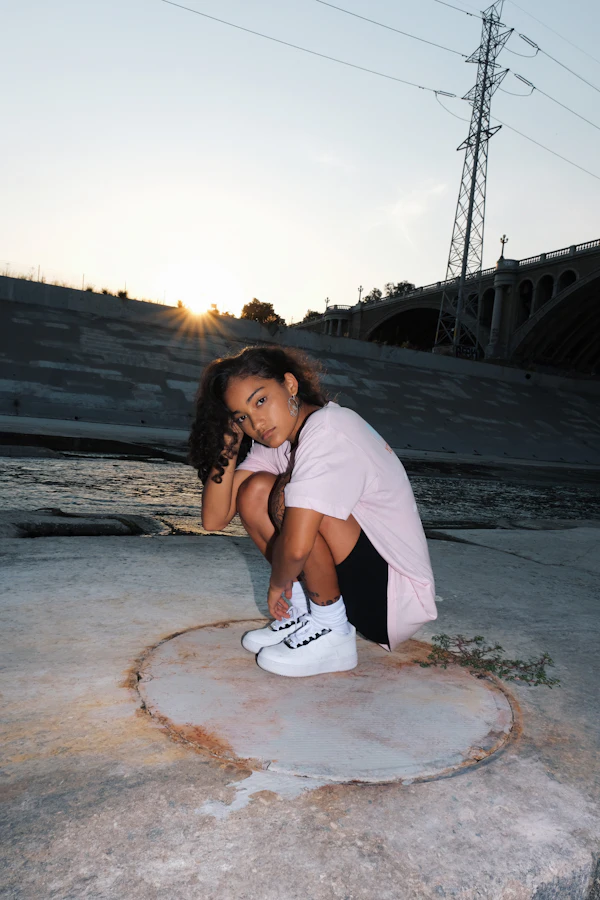 A creator posing at sunset by a bridge