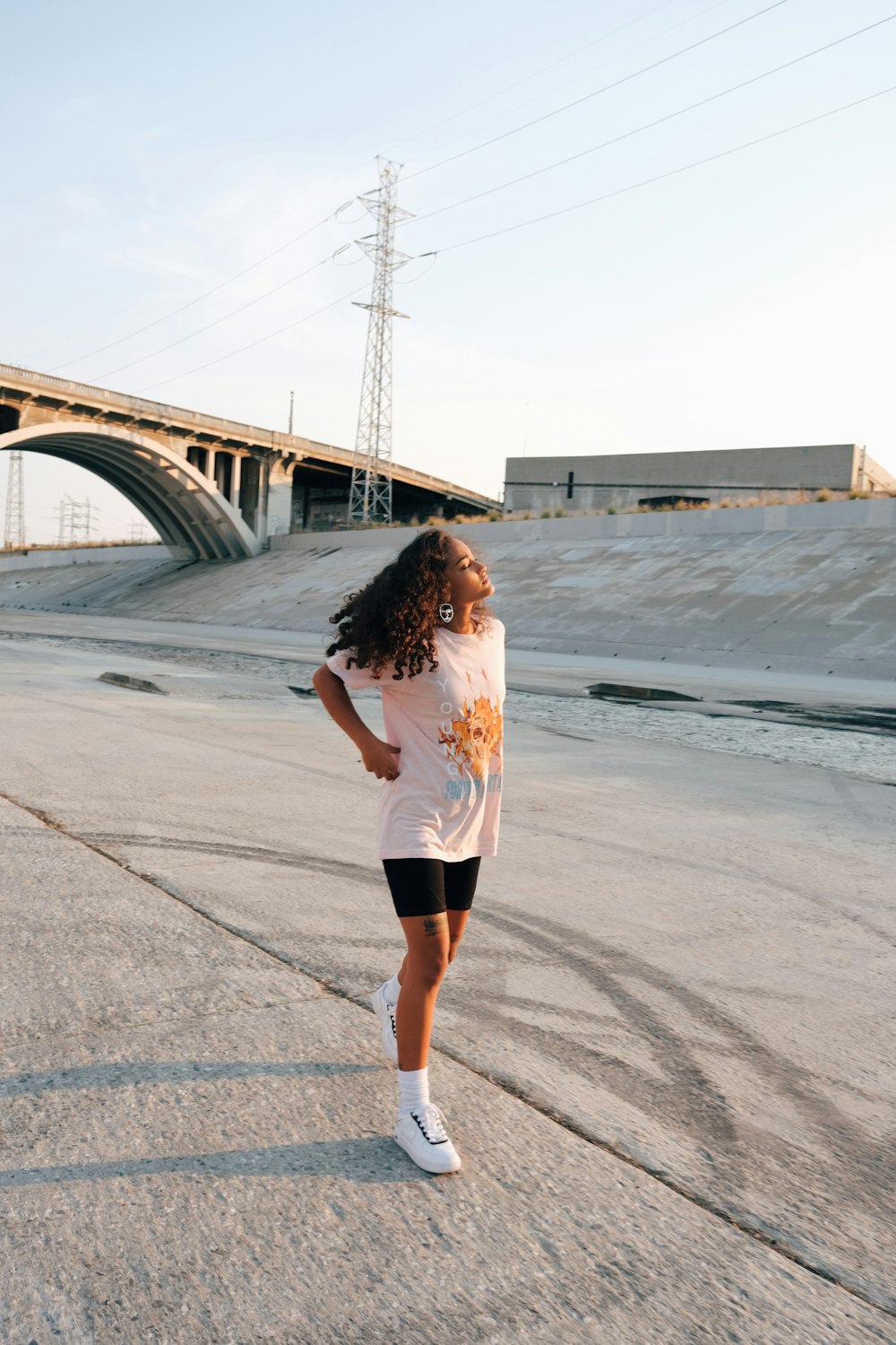 woman in white shirt and black shorts standing on gray concrete road during daytime