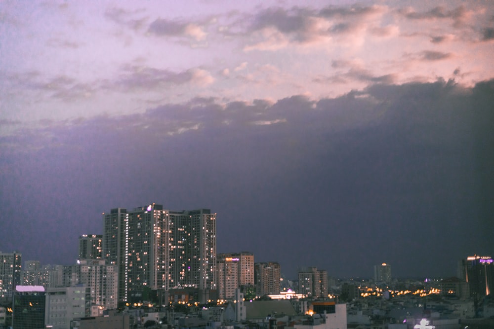 city skyline under gray cloudy sky during night time