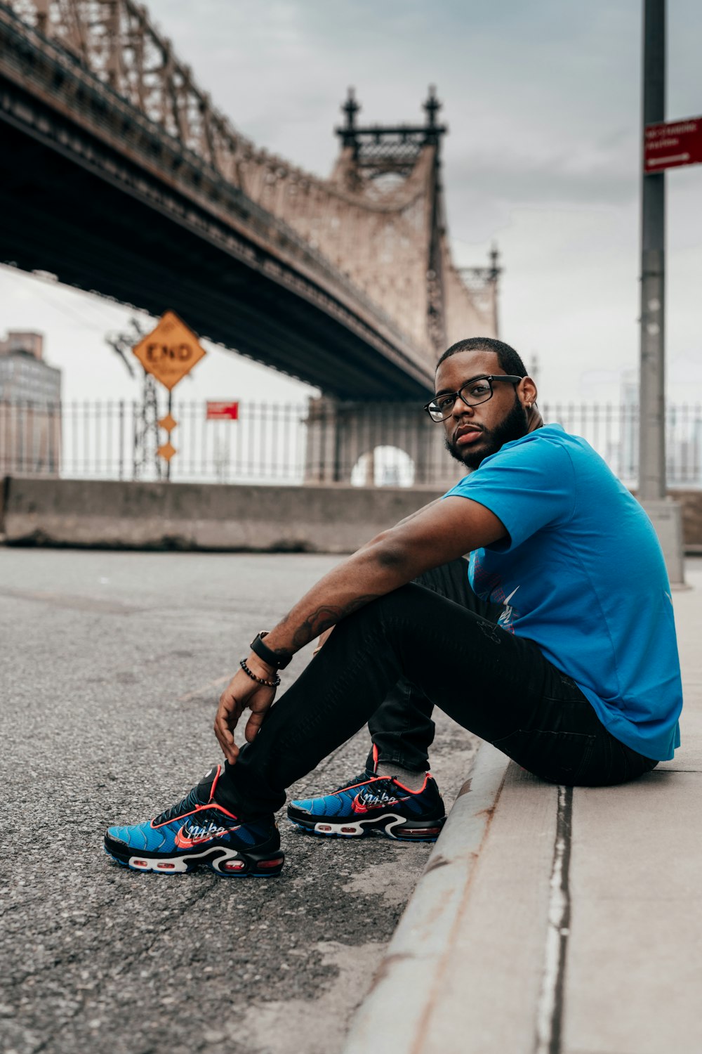 man in blue shirt and black pants sitting on concrete floor