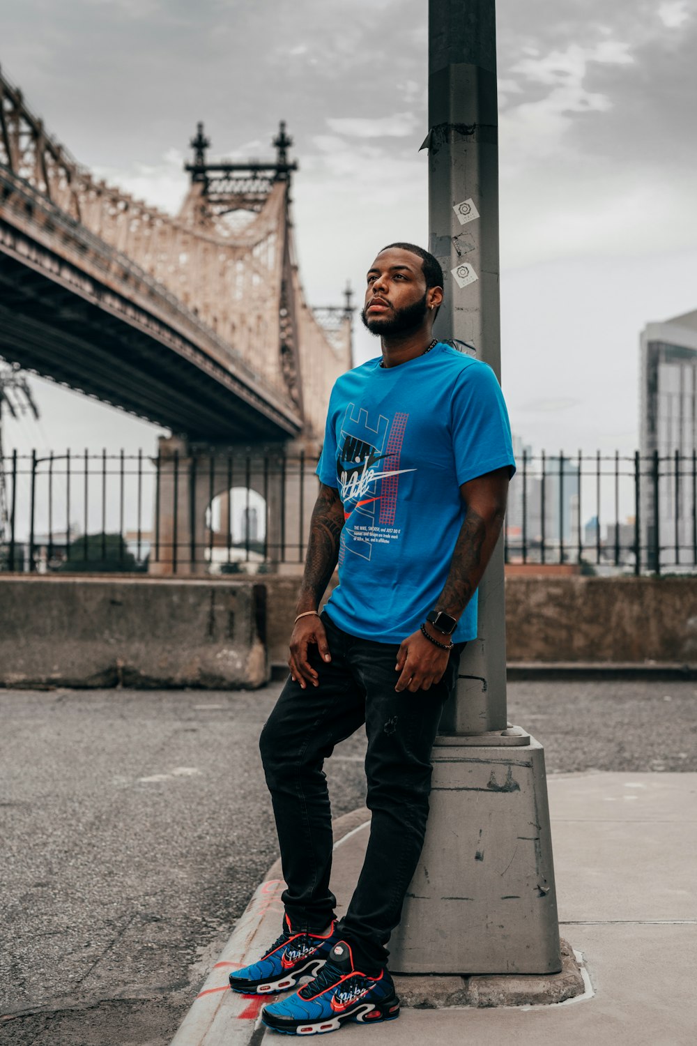 man in blue crew neck t-shirt and black pants standing on gray concrete floor during