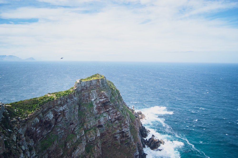 green and gray mountain beside sea under white clouds during daytime