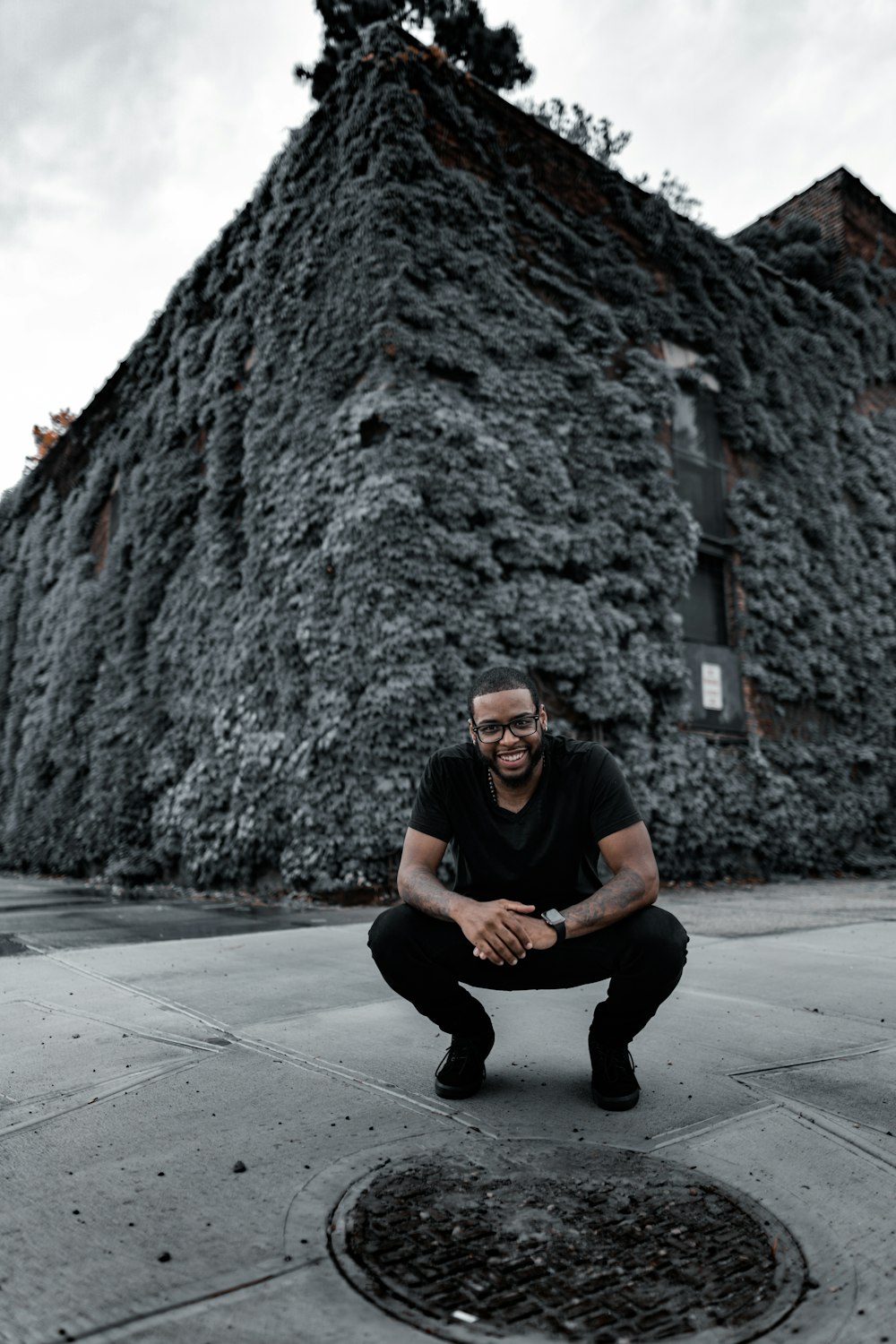 man in black crew neck t-shirt and black pants sitting on gray concrete floor