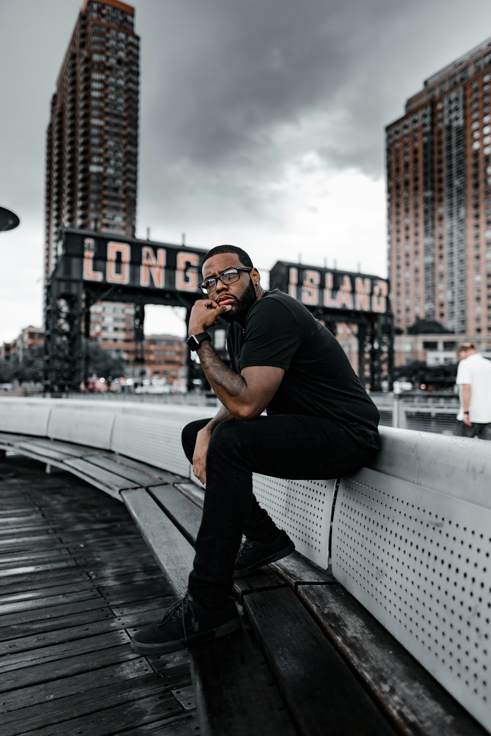 man in black t-shirt and black pants sitting on gray metal railings