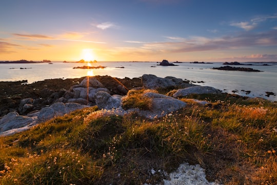 brown and gray rock formation near body of water during sunset in Santec France