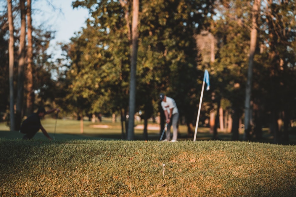 man in white shirt and black pants playing golf during daytime