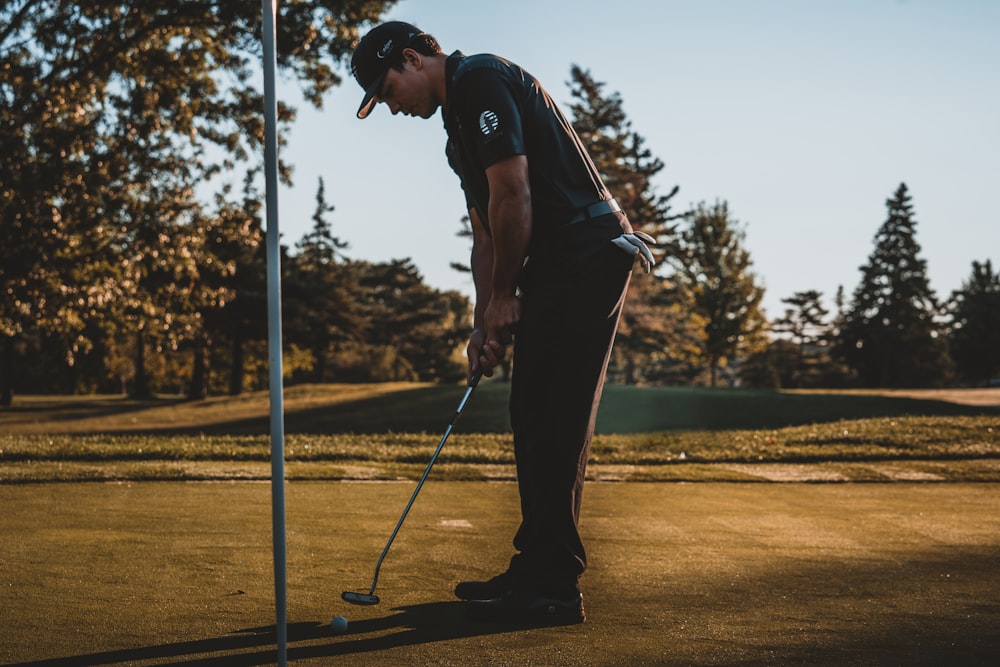 man in black t-shirt and black pants playing golf during daytime