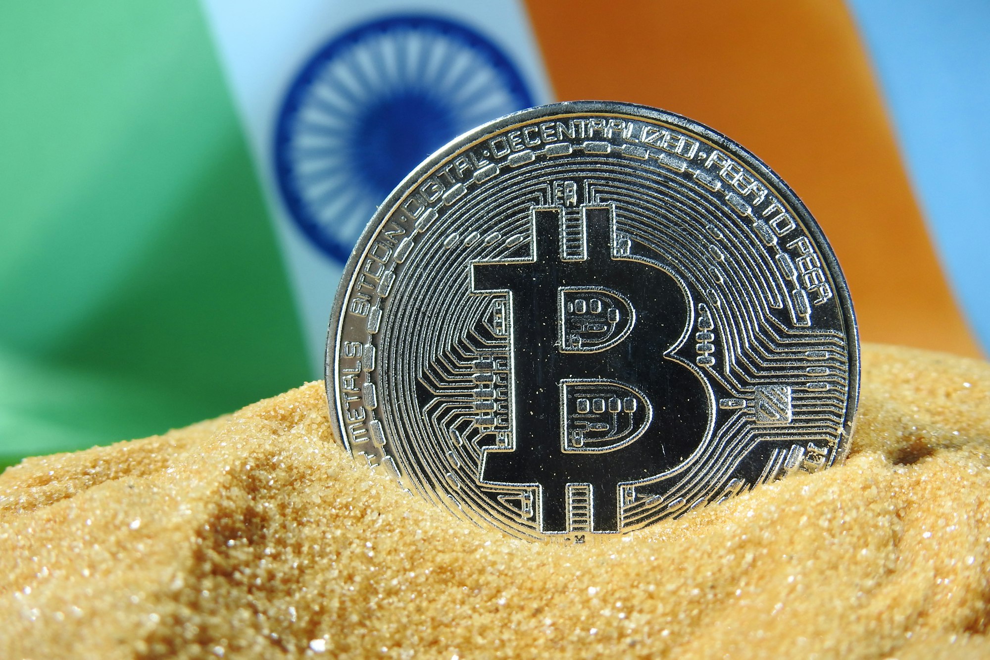 A silver Bitcoin cryptocurrency with India flag in the background