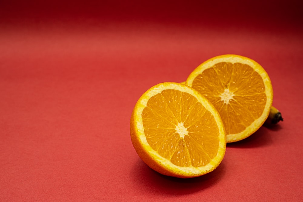 sliced orange fruit on red surface