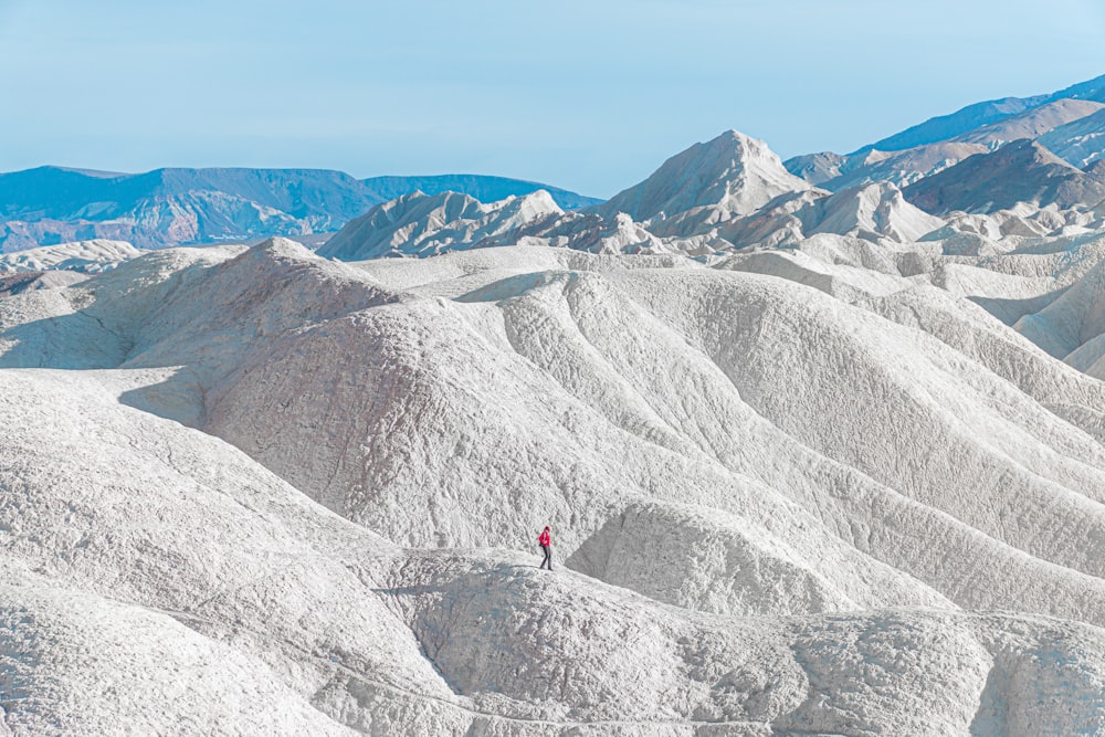 person in red jacket standing on white snow covered mountain during daytime