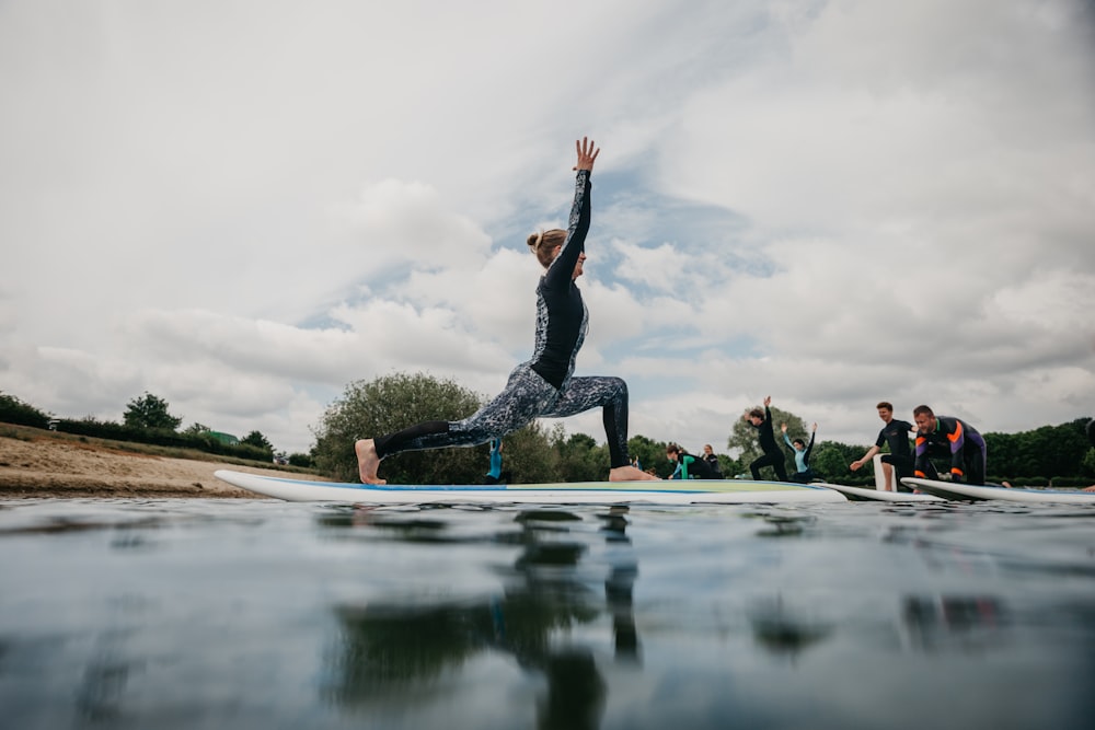 woman in black tank top and black leggings doing yoga on blue yoga mat on water