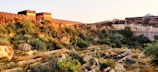 Ancient fort walls bathed in golden morning light, surrounded by lush greenery.