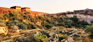 Ancient fort walls bathed in golden light with a lone traveler exploring.
