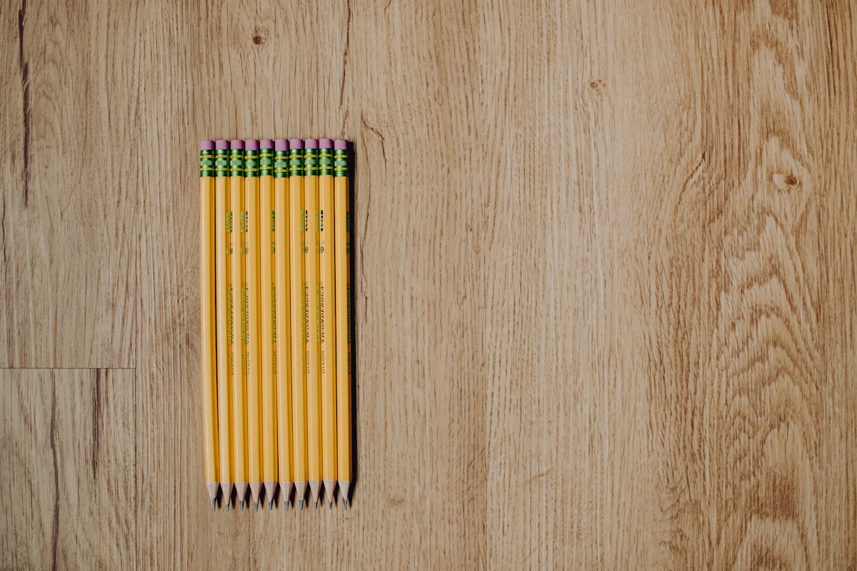 Yellow, green, and red color pencils arranged on a white background, symbolizing organized field trip planning tools.
