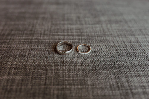 Stacked slender rings with subtle diamond accents on a smooth beige surface.