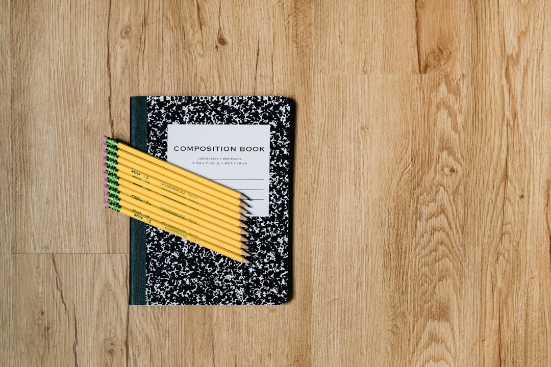 white and black card on brown wooden table, Comp book and #2 pencils laying on wood