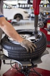 Technician fitting a tire onto a car wheel using specialized tools.