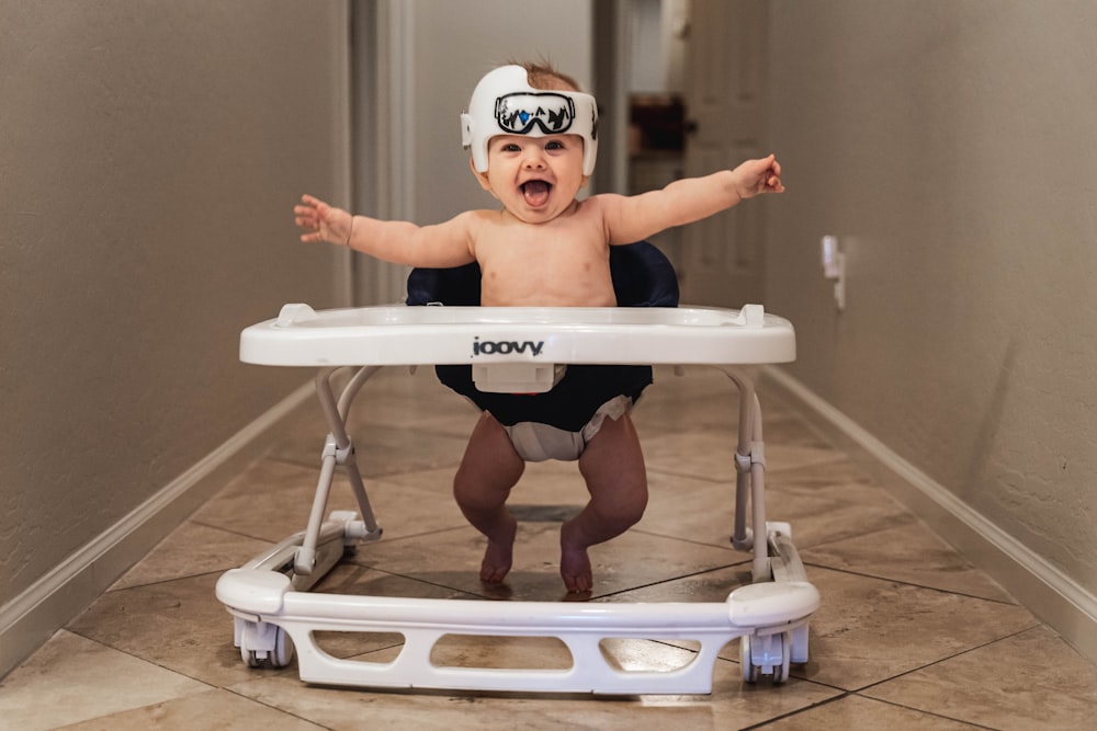 baby in white goggles on white and blue high chair