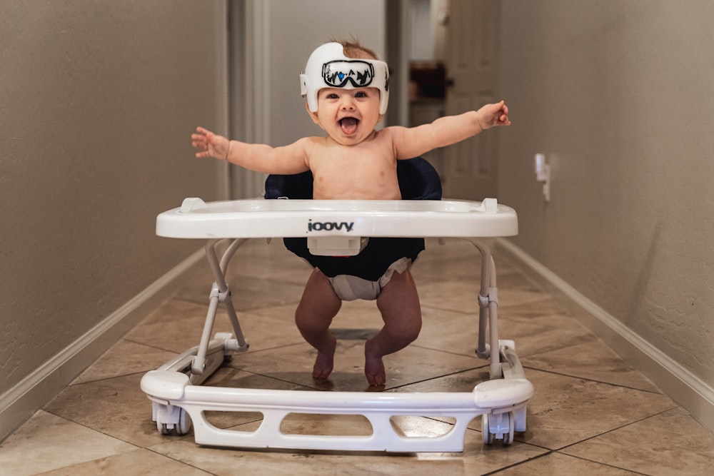 Baby in weißer Brille auf weißem und blauem Hochstuhl