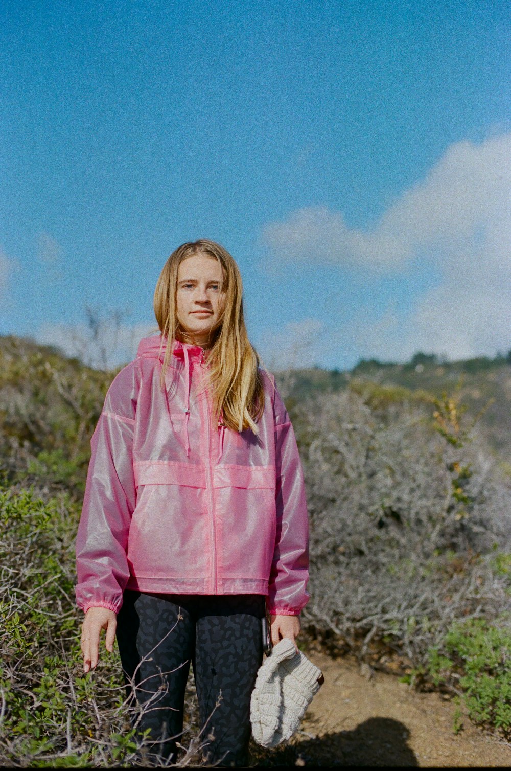 girl in pink hoodie standing on green grass field during daytime
