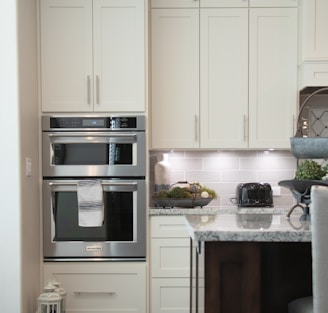 white wooden kitchen cabinet and stainless steel microwave oven