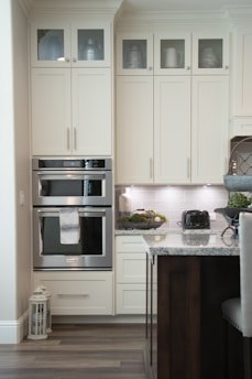 white wooden kitchen cabinet and stainless steel microwave oven