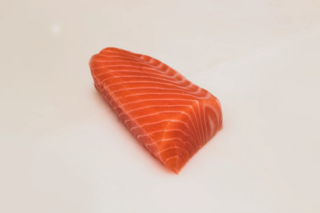 Oven-baked salmon fillet with lemon slices, garlic, and fresh herbs in a baking dish