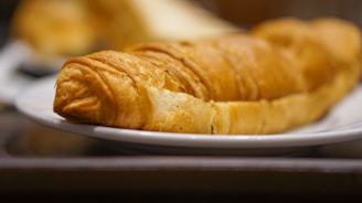 Close-up of a golden-brown croissant with flaky layers on a rustic wooden board.