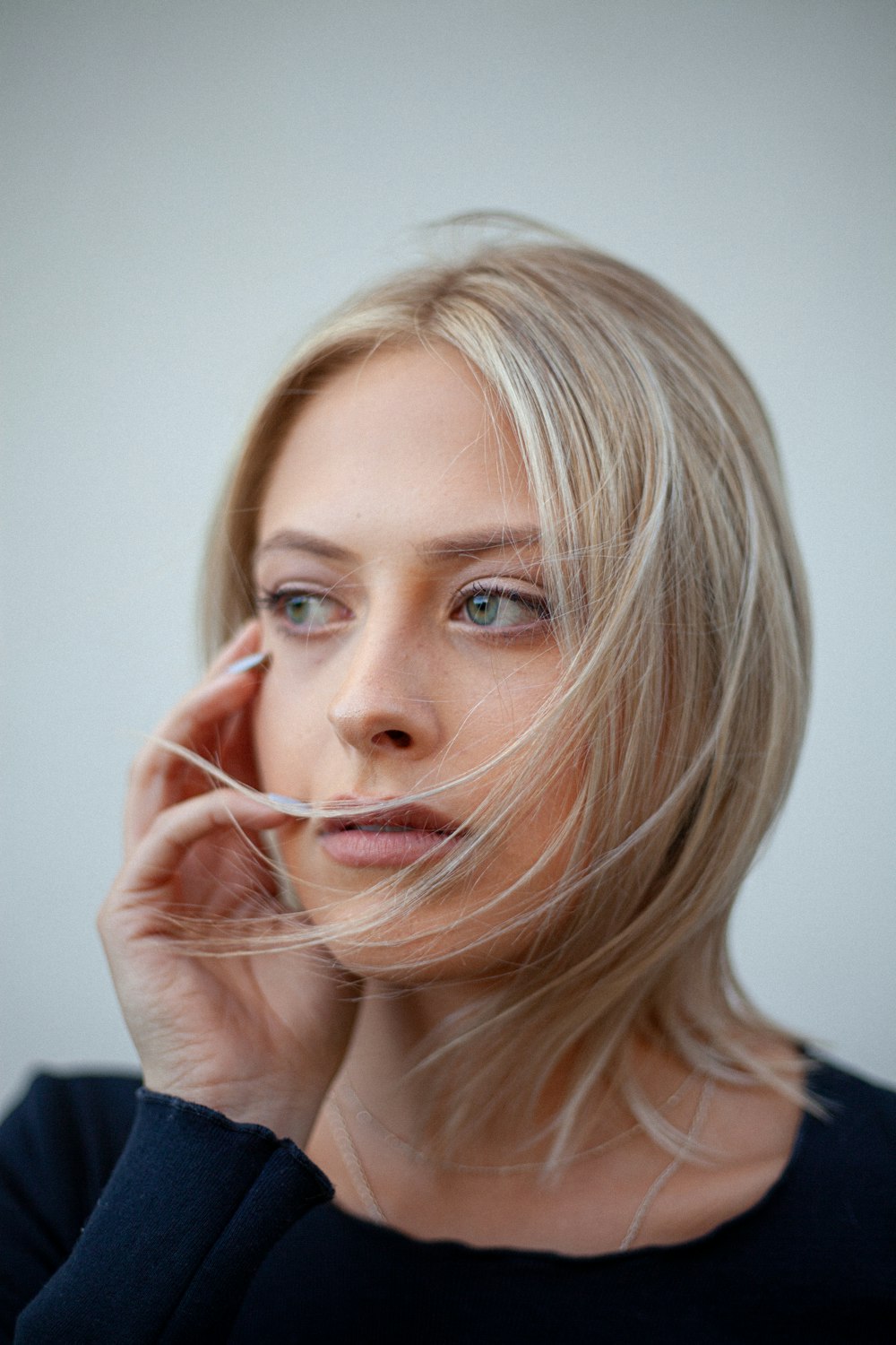 woman in black shirt holding her face