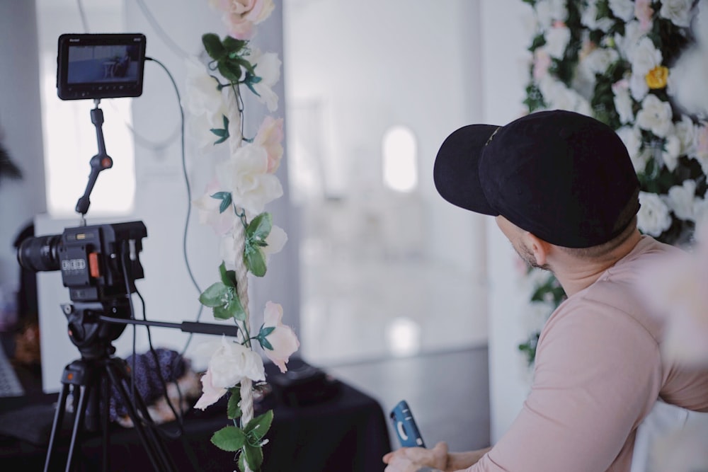 woman in white shirt and black hat holding smartphone