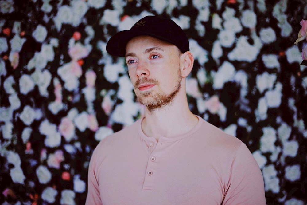 man in pink crew neck shirt and black hat