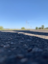 Workers repairing asphalt road under clear sky