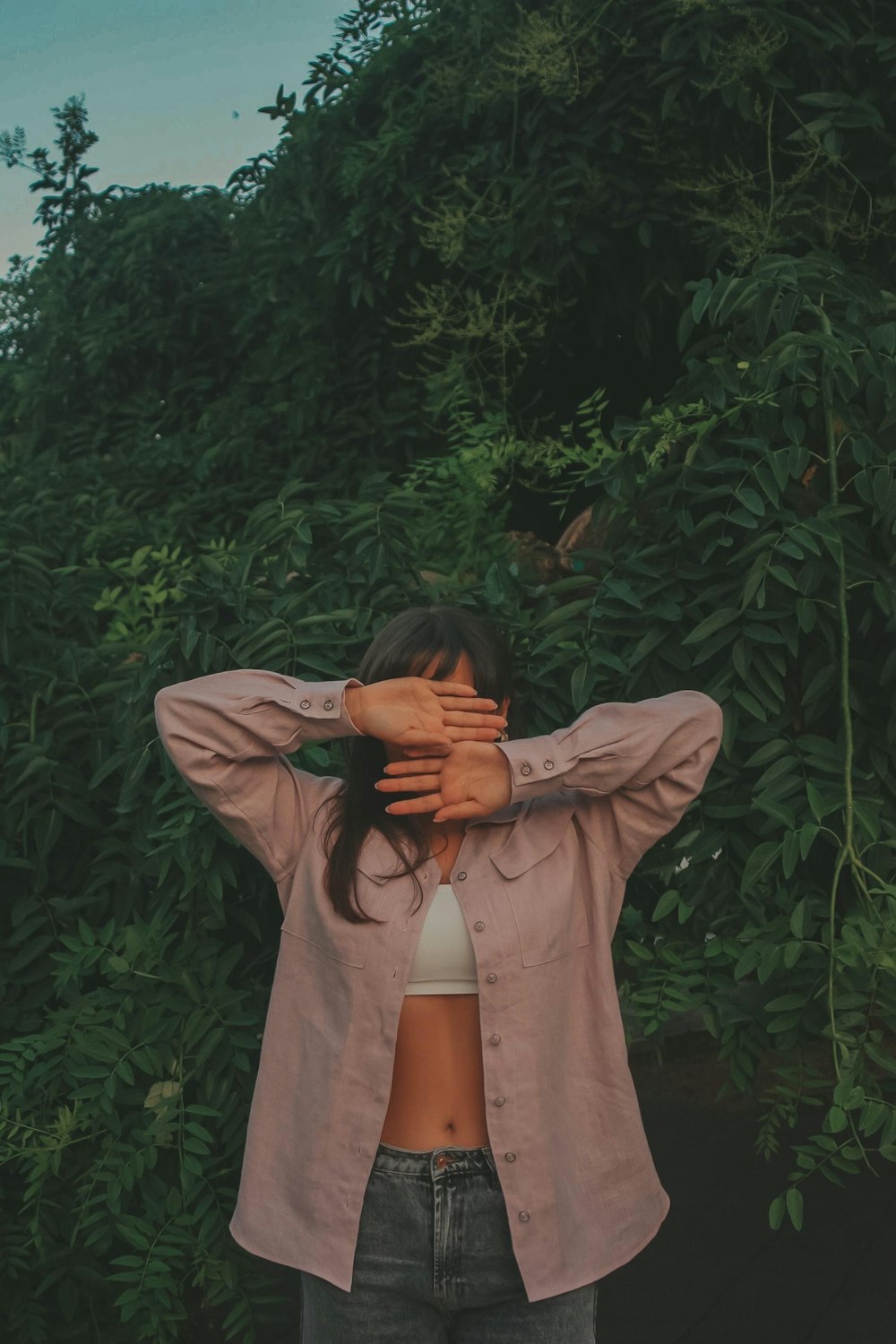 woman in gray long sleeve shirt covering her face with her hands