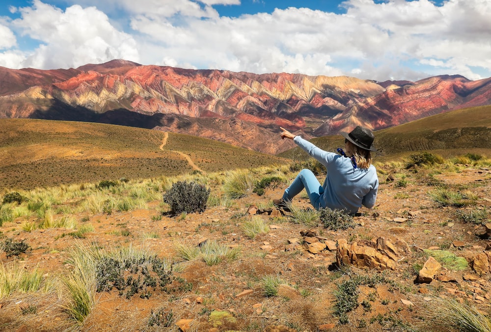 man in white long sleeve shirt and black pants sitting on brown rock during daytime