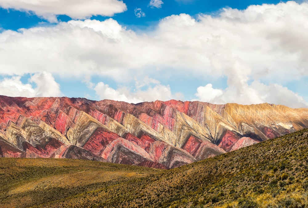 montañas marrones y grises bajo nubes blancas y cielo azul durante el día