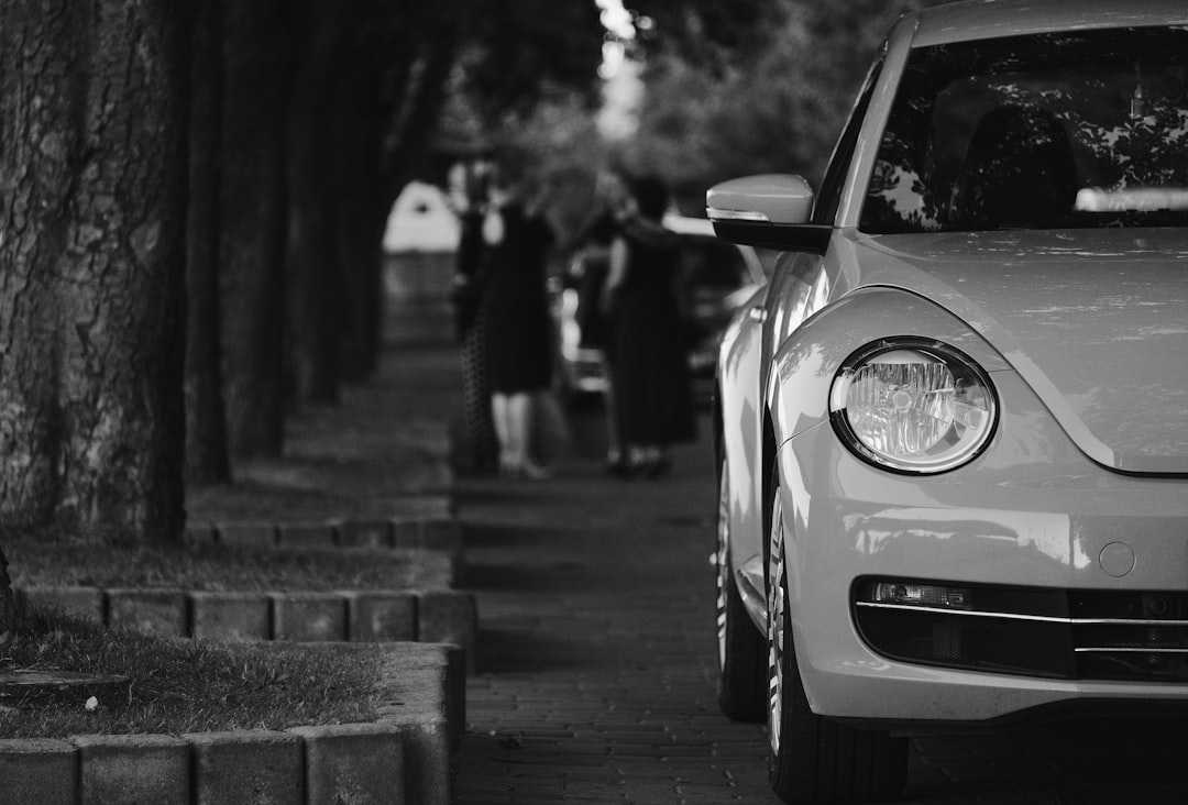 grayscale photo of car parked on sidewalk