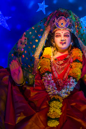 A statue of Durga Devi wearing a red sari and floral garlands in Mumbai