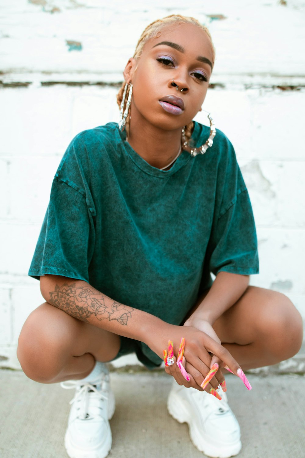 girl in green crew neck t-shirt sitting on white concrete floor