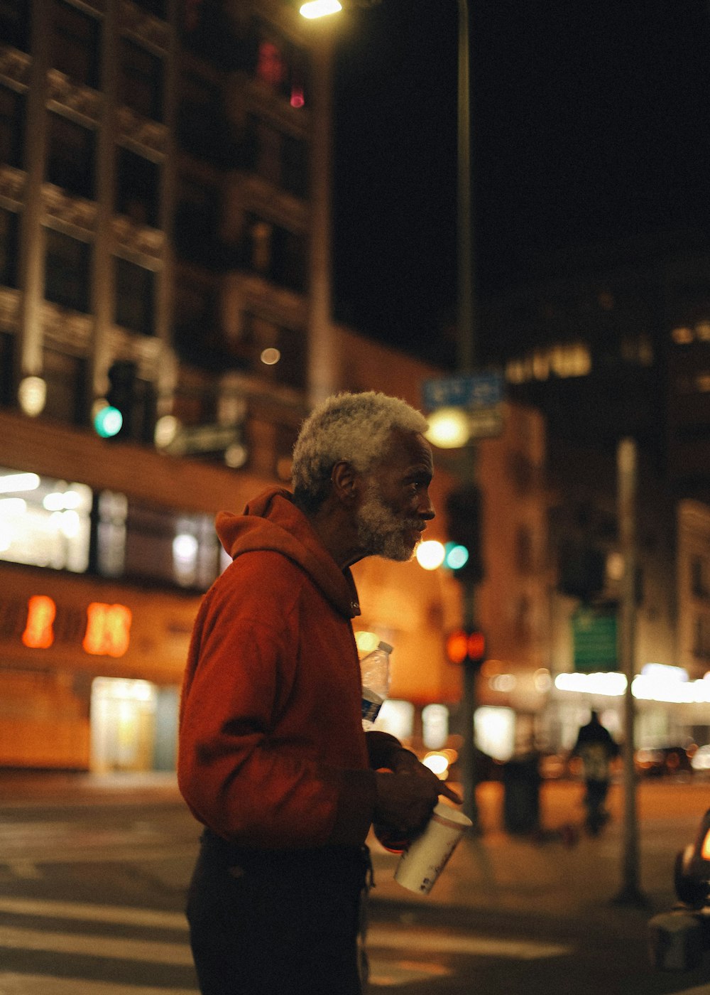 man in brown hoodie standing near building during night time