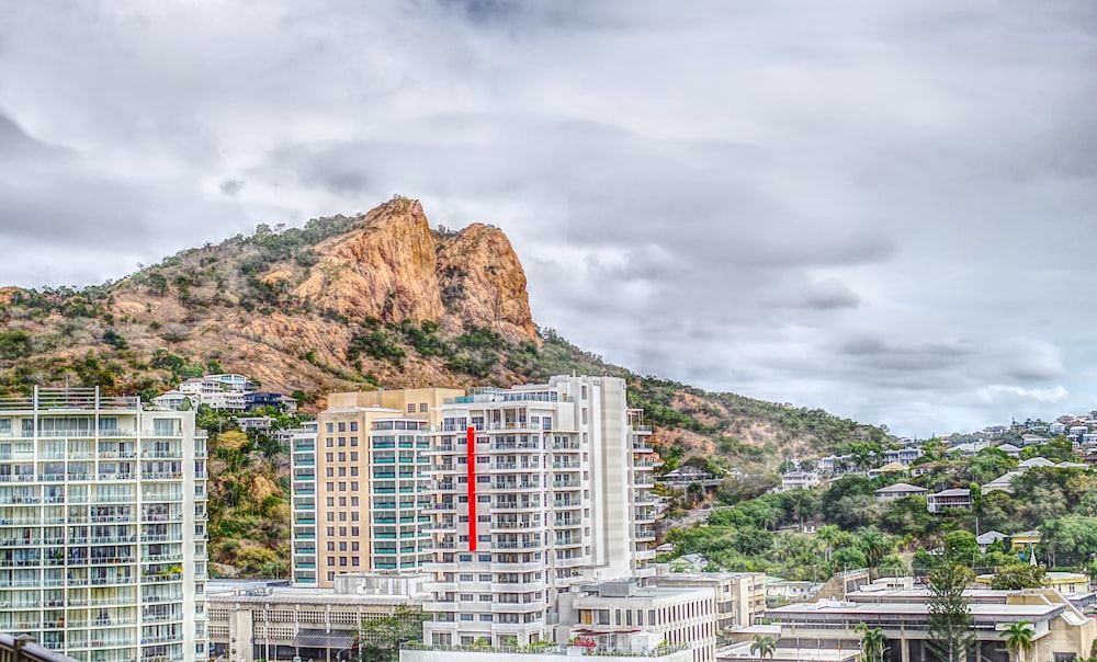 white and red concrete building near mountain under cloudy sky during daytime