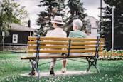 man and woman sitting on brown wooden bench during daytime