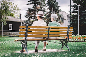 Couple sharing laughs on a cozy park bench surrounded by blooming flowers.