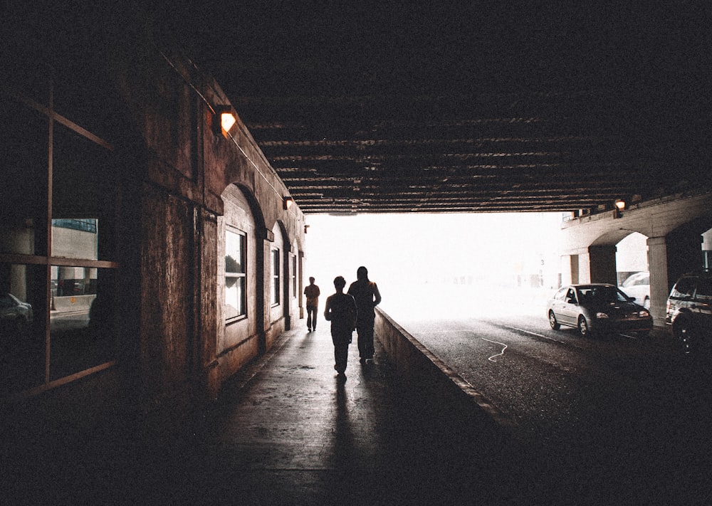 silhouette of 2 people walking on sidewalk during daytime